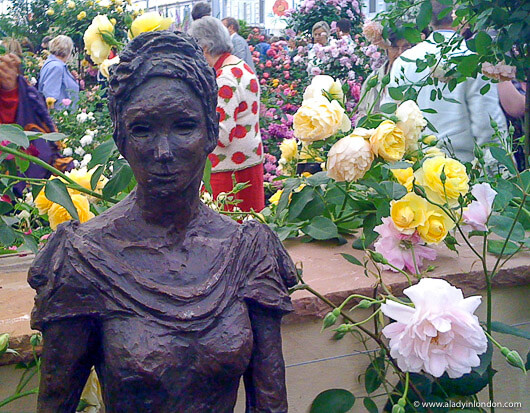 Sculpture of a woman in front of roses at the Chelsea Flower Show in London