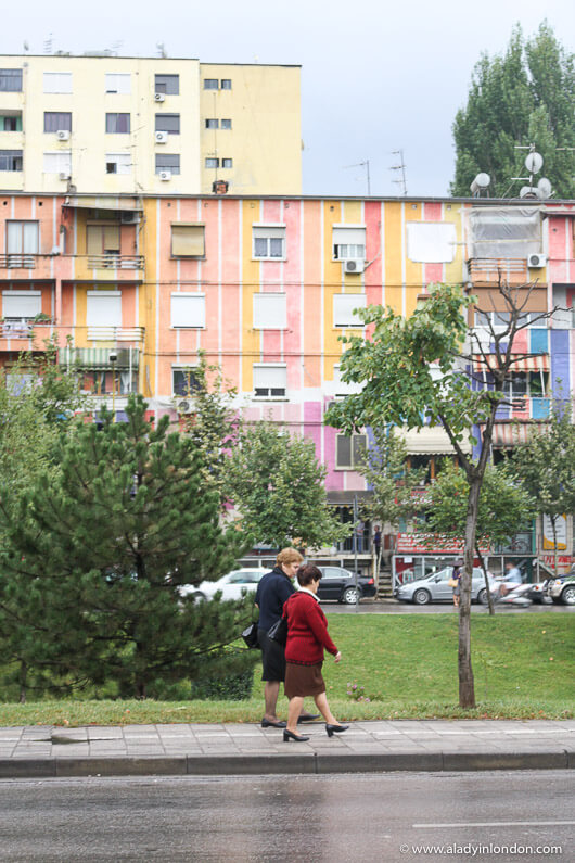 Women walking in front of a colorful communist building in Tirana